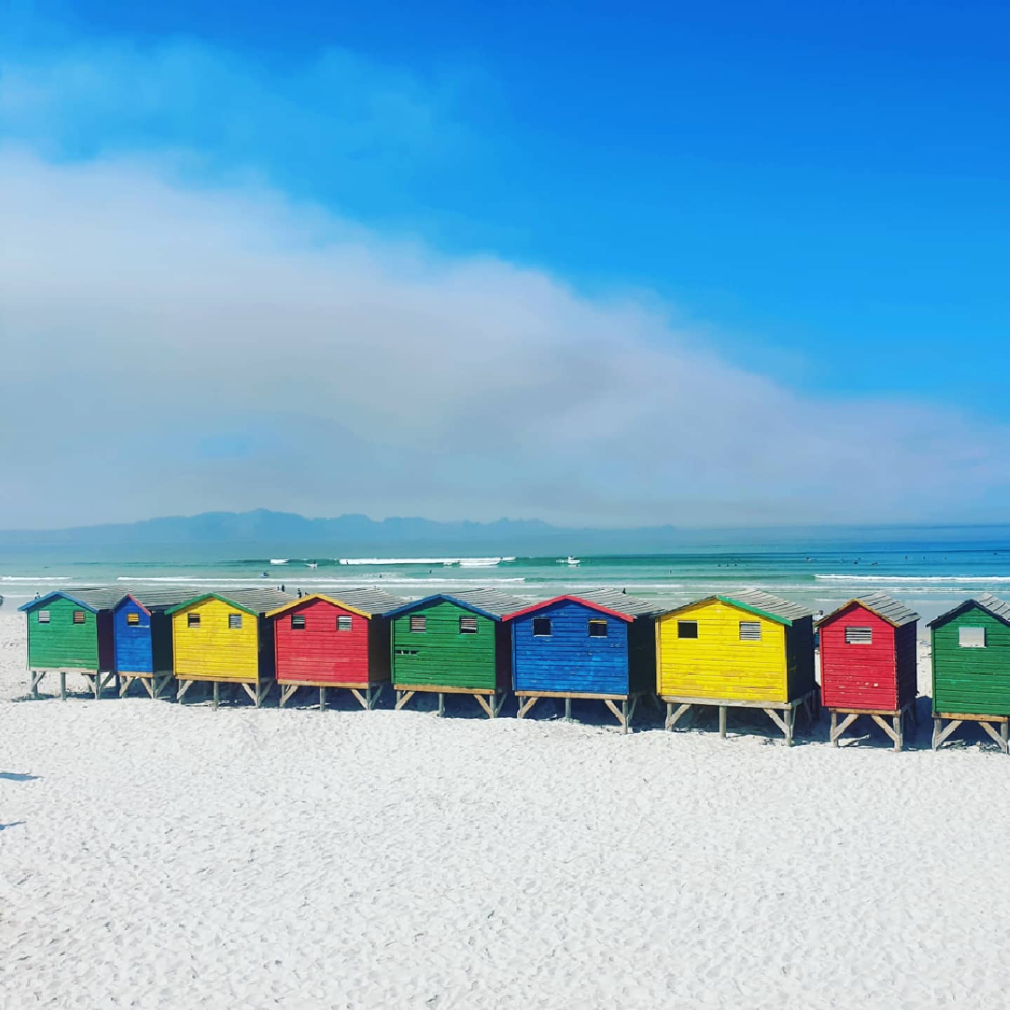 Muizenberg bathing boxes and surfers with glassy waves